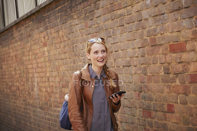 Mujer caminando por la pared de ladrillo, Londres, Reino Unido - foto de stock