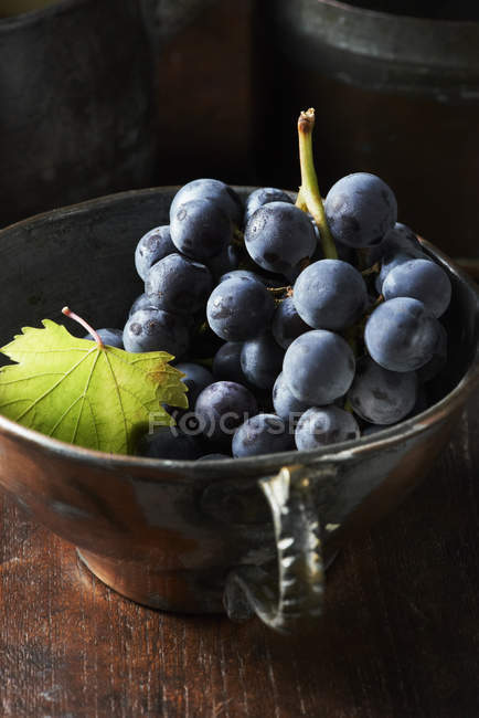 Vista de alto ângulo de cacho de uvas pretas em xícara de chá vintage — Fotografia de Stock