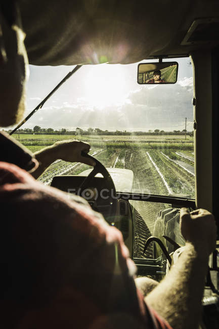 Over shoulder view through tractor windscreen on furrowed field — Stock Photo