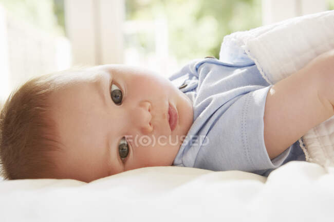 Голубоглазый мальчик, лежащий на кровати — стоковое фото