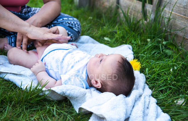 Кадр, на котором женщина наносит крем, меняя подгузник сыну в саду — стоковое фото
