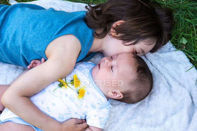 Boy hugging baby brother in garden — Stock Photo