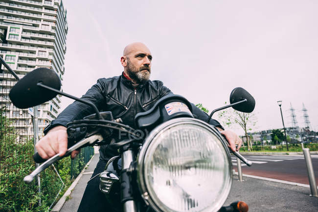 Älterer männlicher Motorradfahrer sitzt auf Motorrad auf Stadtstraße — Stockfoto