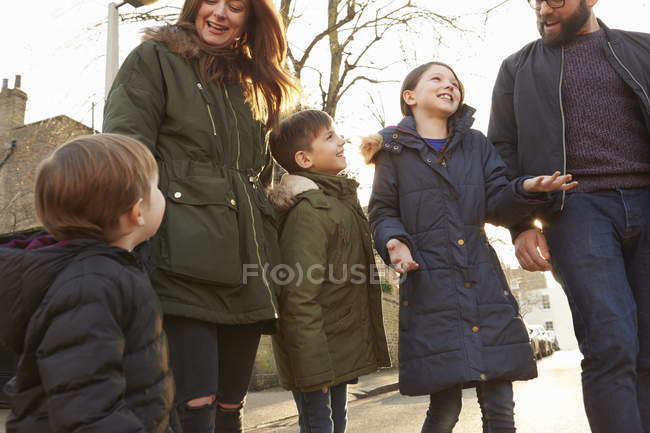 Pareja adulta y tres niños paseando por la calle - foto de stock