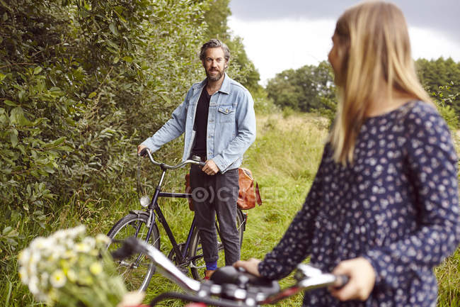 Female cyclist looking back at boyfriend on rural path — Stock Photo