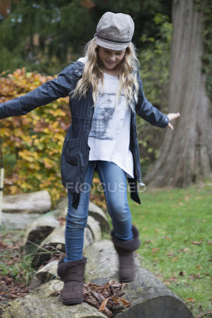 Girl stepping over logs in park — Stock Photo