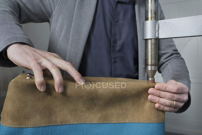 Man applying bag feet to leather holdall — Stock Photo