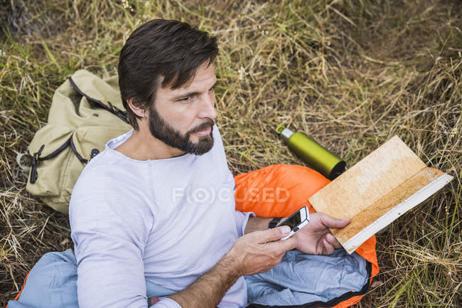 Pianificazione sacchi a pelo uomo con mappa e smartphone nella foresta, Deer Park, Città del Capo, Sud Africa — Foto stock