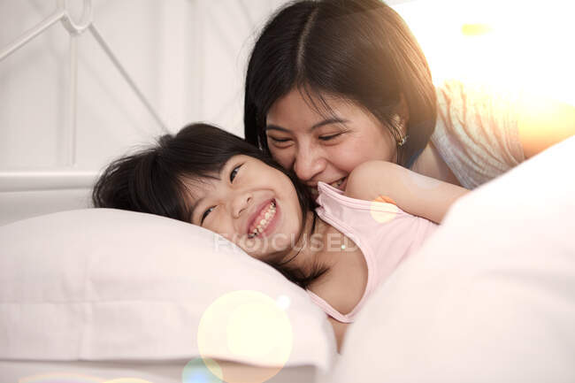 Giovane madre cinese e figlia sdraiati a letto insieme a casa — Foto stock