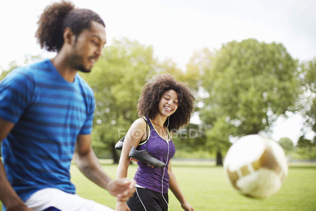 Young soccer couple playing keepy uppy in park — Stock Photo