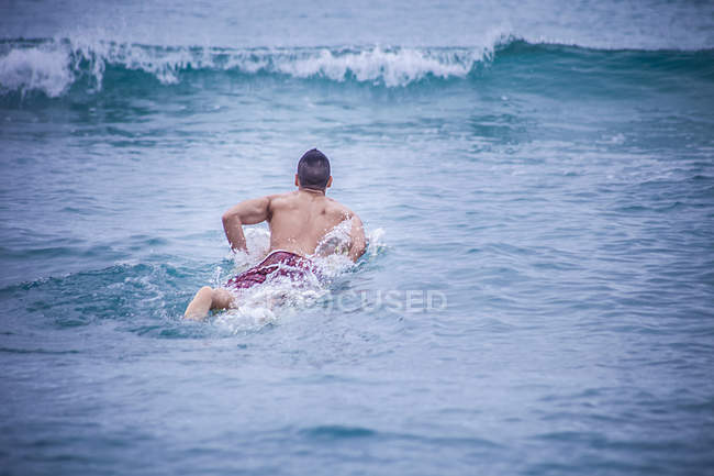 Junger männlicher Surfer liegt auf Surfbrett im Meer, cagliari, sardinien, italien — Stockfoto