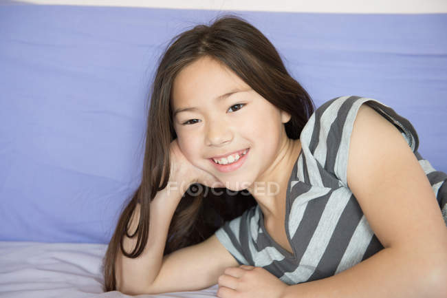 Porträt eines lächelnden Mädchens, das auf dem Bett liegt — Stockfoto