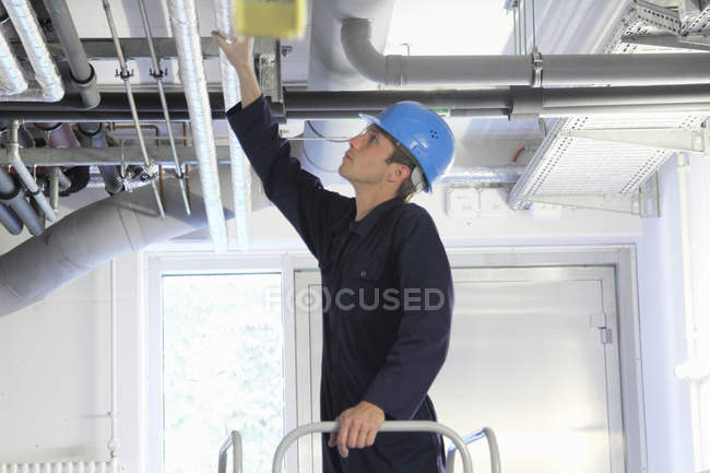 Engenheiro masculino verificando encanamentos industriais na fábrica — Fotografia de Stock