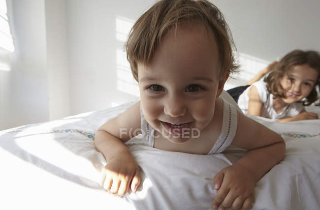 Close-up candid portrait of female toddler and sister lying on bed — Stock Photo