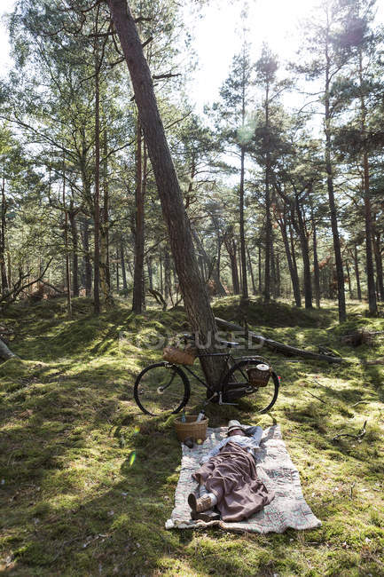 Mature female forager lying on blanket in forest — Stock Photo
