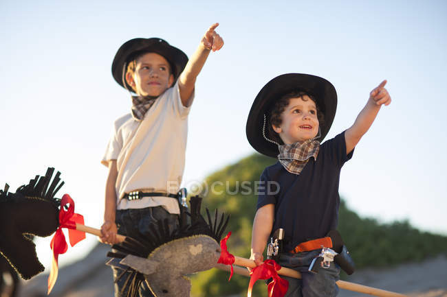 Zwei als Cowboys verkleidete Brüder zeigen von Sanddünen — Stockfoto