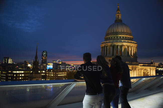 Vista trasera en silueta de dos parejas jóvenes mirando hacia St Pauls por la noche, Londres, Reino Unido - foto de stock