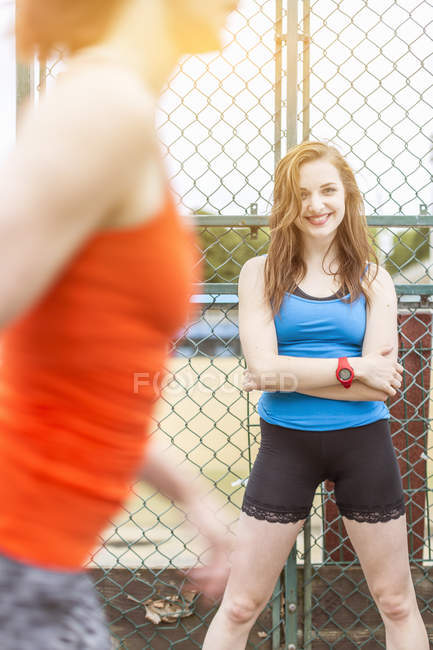 Runner passing young woman standing beside sports ground, London, UK — Stock Photo