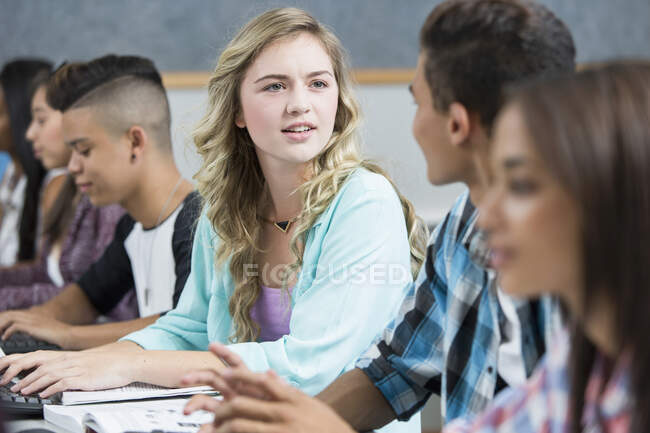 Ряд подростков старшеклассников разговаривают в компьютерном классе — стоковое фото