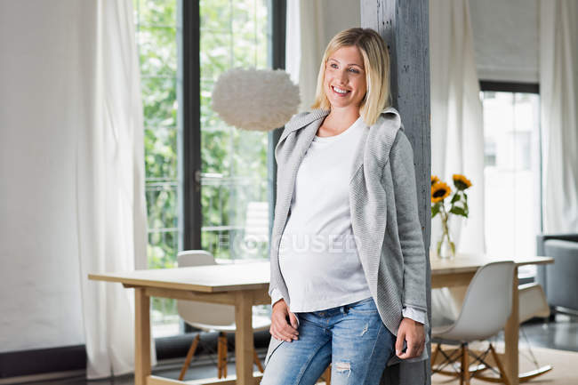 Счастливая полная беременность молодой женщины на кухне — стоковое фото