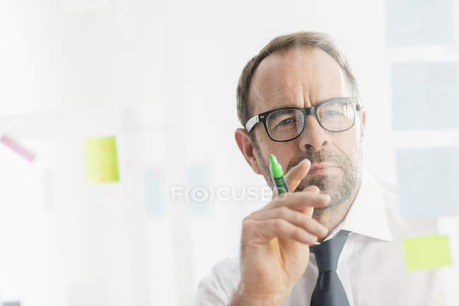 Businessman working on ideas at office glass wall — Stock Photo