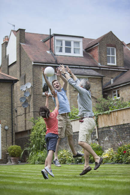 Familia de tres generaciones jugando con el fútbol en el jardín - foto de stock