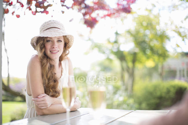 Retrato de una hermosa mujer joven en la mesa en el restaurante jardín - foto de stock