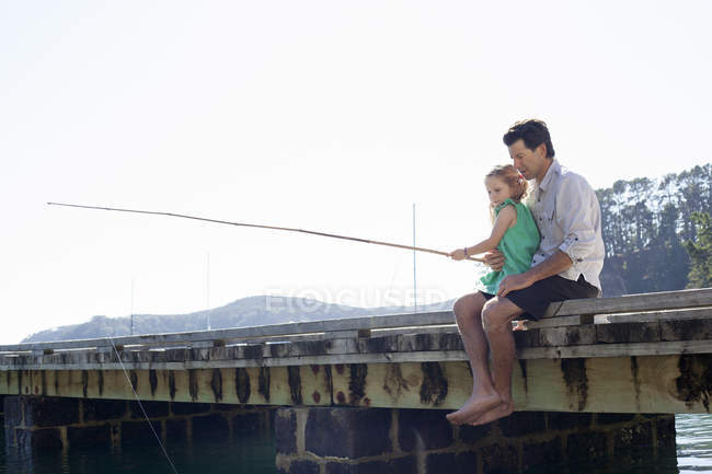 Mature man and daughter fishing on sea pier, New Zealand — Stock Photo