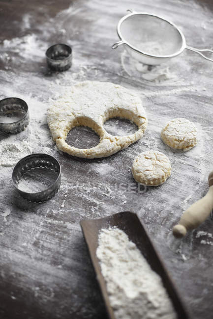 Baking preparation with scone dough and pastry cutters on table — Stock Photo