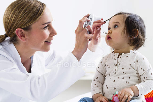 Pediatra revisando los ojos del niño - foto de stock