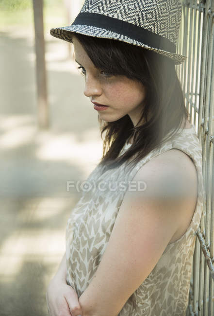 Sullen jeune femme derrière la clôture du parc — Photo de stock