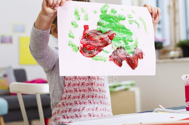 Cropped image of girl holding up painting at home — Stock Photo