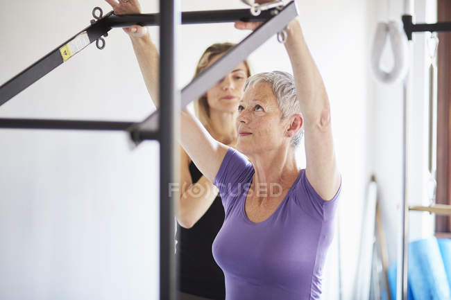 Female student and tutor practicing pilates on trapeze table in pilates gym — Stock Photo