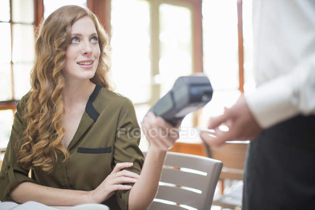 Jeune femme remise lecteur de carte de machine à serveur dans le restaurant — Photo de stock