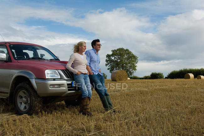 Mother and son leaning against four wheeled drive in harvested field — Stock Photo