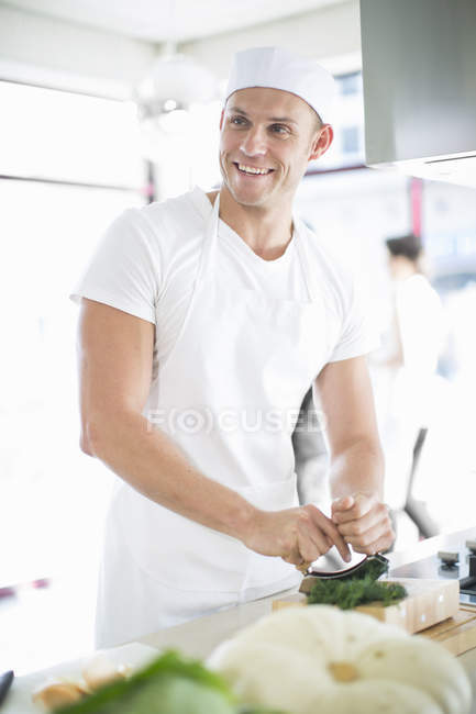 Chef macho mezclando hierbas picantes en cocina comercial - foto de stock