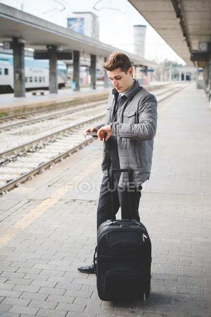 Portrait of young businessman commuter checking wristwatch for the time at train station. — Stock Photo