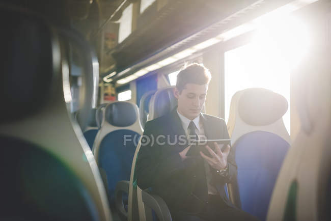 Portrait de jeune homme d'affaires banlieusard utilisant tablette numérique sur le train
. — Photo de stock