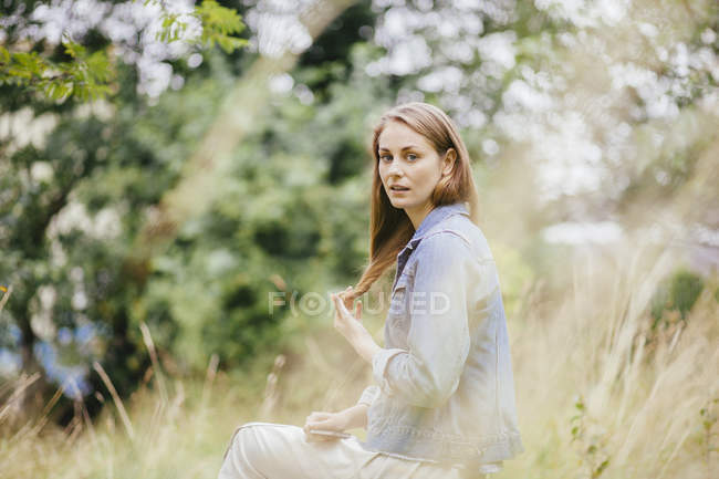 Portrait of young woman with hand in hair in field — Stock Photo