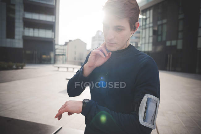 Молодий чоловік бігун перевіряє пульс шиї на міській площі — стокове фото