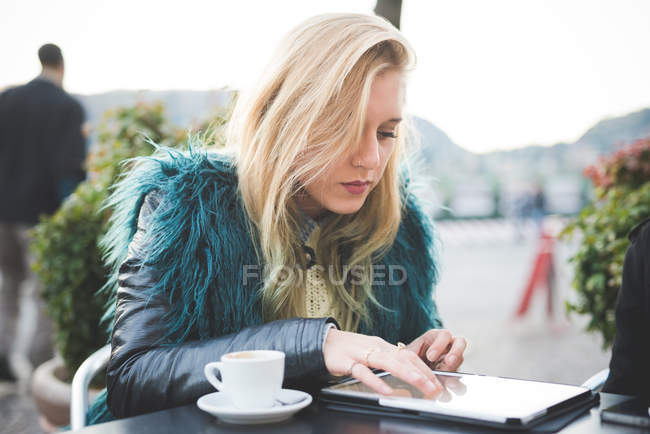 Молода жінка використовує цифровий планшет у тротуарному кафе — стокове фото