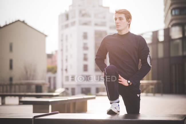 Young male runner doing warm up in city square — Stock Photo