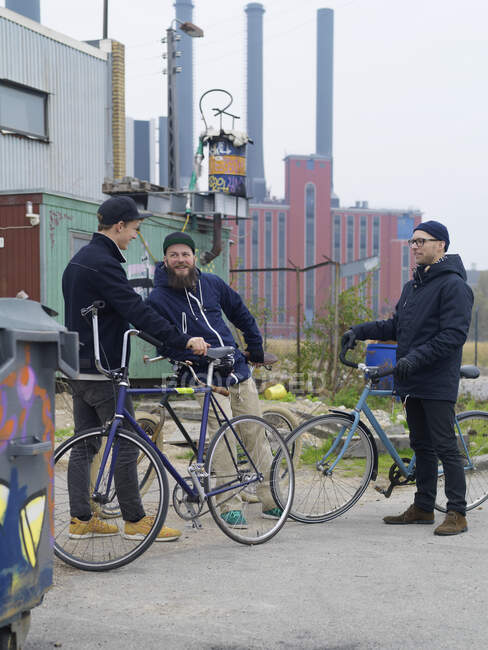 Ciclistas urbanos charlando cerca de la fábrica - foto de stock