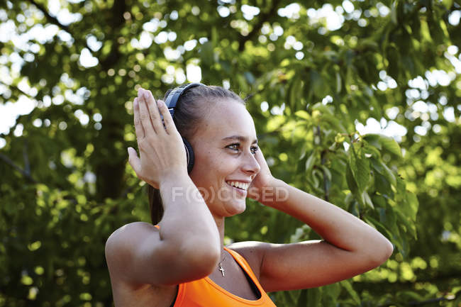 Jeune coureuse ajustant les écouteurs — Photo de stock