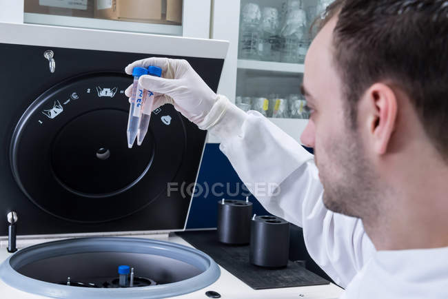 Cancer research laboratory, scientist placing cells into centrifuge — Stock Photo