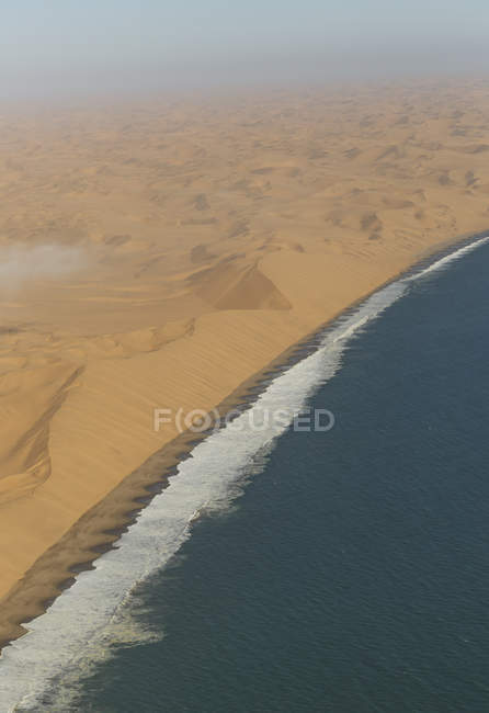 Воздушный вид волн для серфинга на береговой линии и песчаных дюнах — стоковое фото