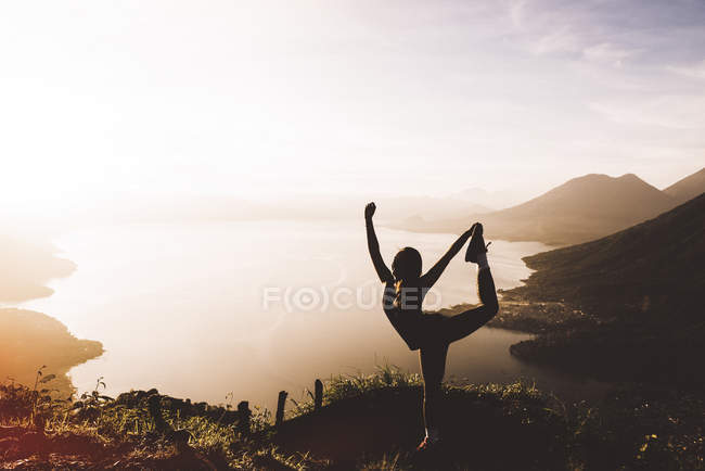 Silhouetted view of young woman posing at sunset above Lake Atitlan, Guatemala — Stock Photo
