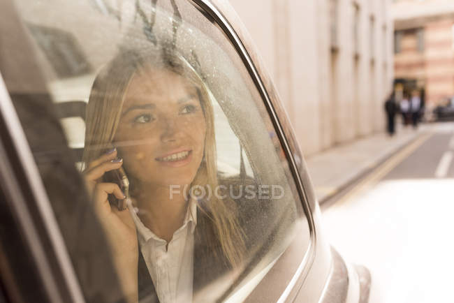 Businesswoman looking out of black cab, London, UK — Stock Photo