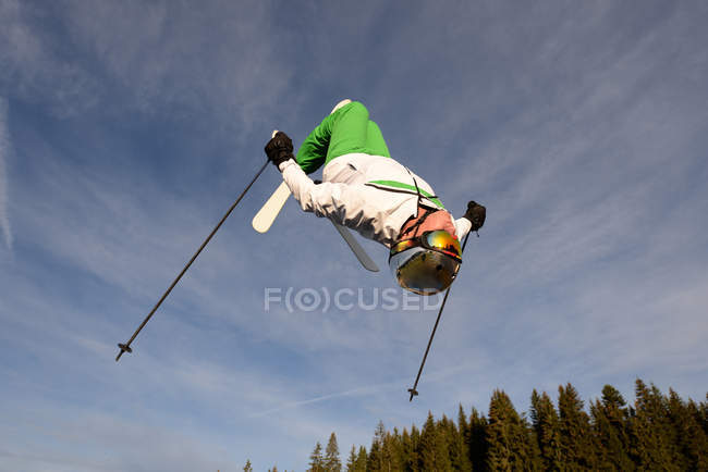 Man backflipping upside down mid air whilst freestyle ski jumping — Stock Photo