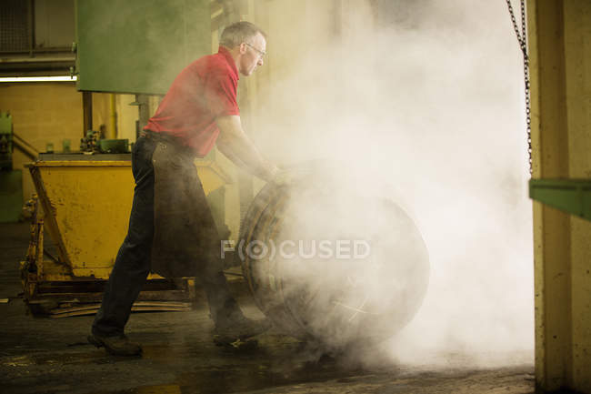 Male cooper rolling whisky cask in cooperage — Stock Photo